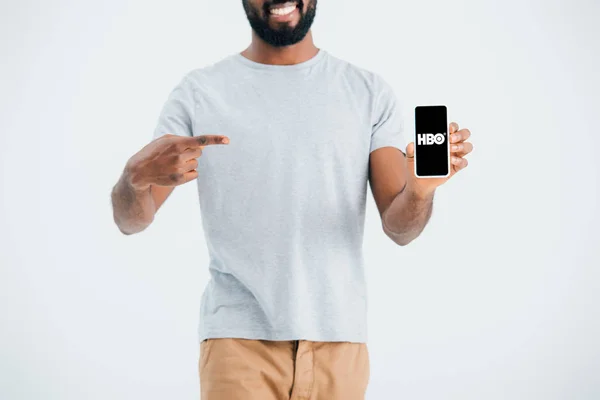 KYIV, UKRAINE - 17 MAI 2019 : vue recadrée d'un homme afro-américain pointant du doigt un smartphone avec l'application HBO, isolé sur gris — Photo de stock