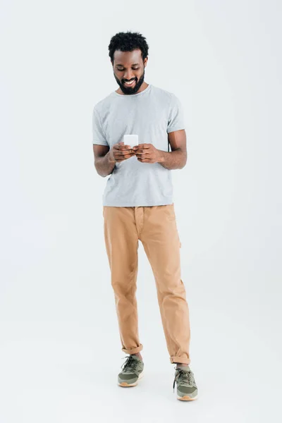 Hombre afroamericano feliz usando el teléfono inteligente, aislado en gris - foto de stock