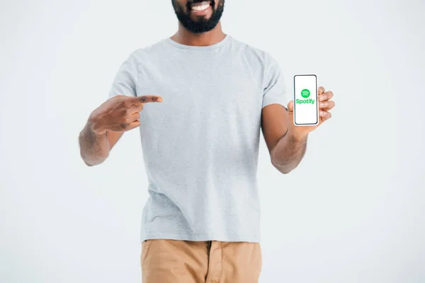 KYIV, UKRAINE - MAY 17, 2019: cropped view of african american man pointing at smartphone with spotify app, isolated on grey — Stock Photo