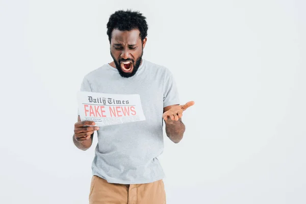 Homme afro-américain agressif criant avec journal avec de fausses nouvelles isolé sur gris — Photo de stock