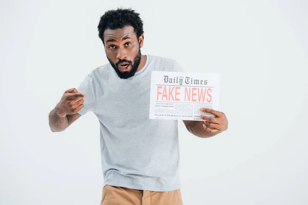 Shocked african american man pointing at newspaper with fake news isolated on grey — Stock Photo