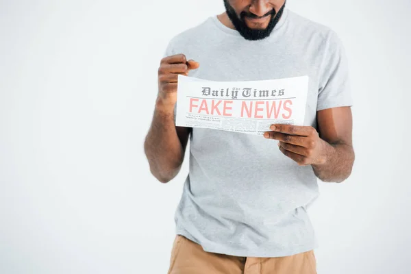 Vue recadrée d'un homme afro-américain confus lisant un journal avec de fausses nouvelles isolées sur gris — Photo de stock