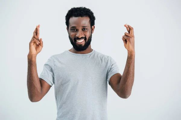 Sorridente afro-americano homem com dedos cruzados isolado em cinza — Fotografia de Stock