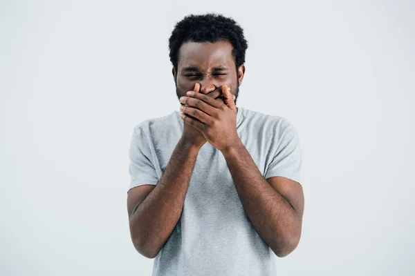 Handsome emotional african american man in grey t-shirt closing mouth isolated on grey — Stock Photo