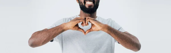 Vista ritagliata di felice uomo africano americano in t-shirt grigia mostrando il segno del cuore isolato sul grigio — Foto stock
