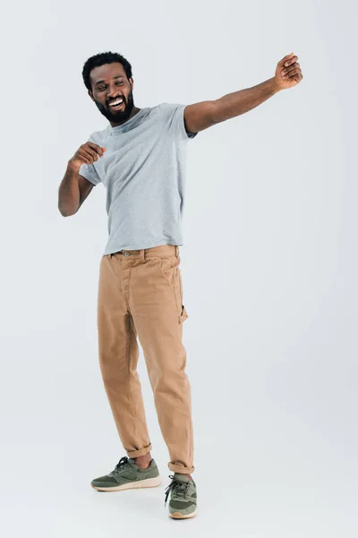 Щасливий афроамериканський чоловік у сірій футболці танцює ізольовано на сірому — стокове фото