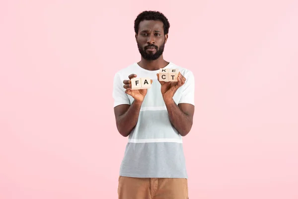 Homem afro-americano segurando cubos alfabeto com palavra de fato, isolado em rosa — Fotografia de Stock