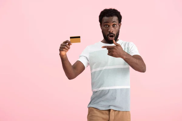 Shocked african american man pointing at credit card isolated on pink — Stock Photo