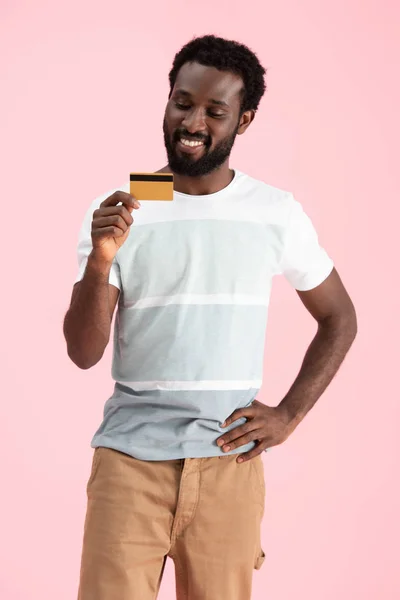 Sonriente afroamericano hombre mostrando tarjeta de crédito aislado en rosa - foto de stock