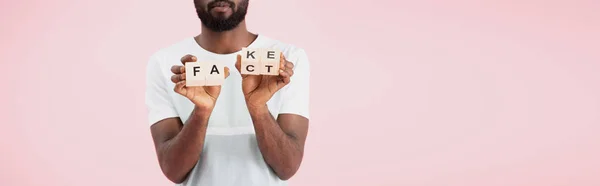 Vista cortada do homem americano africano segurando blocos de alfabeto com palavra fato, isolado em rosa — Fotografia de Stock