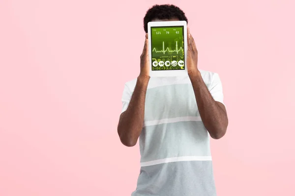 Афроамериканський чоловік, що показує цифровий планшет із додатком для здоров'я, ізольований на рожевому — стокове фото