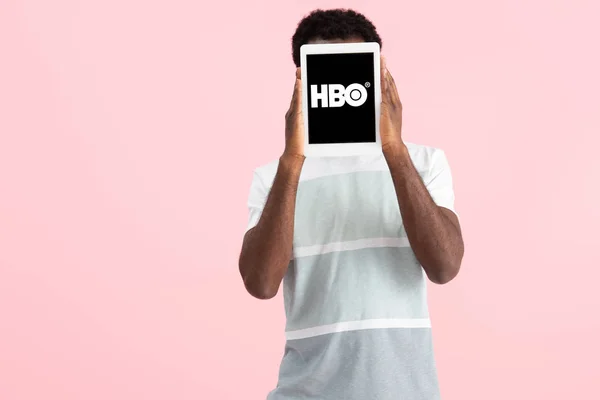 KYIV, UCRANIA - 17 DE MAYO DE 2019: hombre afroamericano gritando y mostrando tableta digital con la aplicación HBO, aislado en rosa - foto de stock