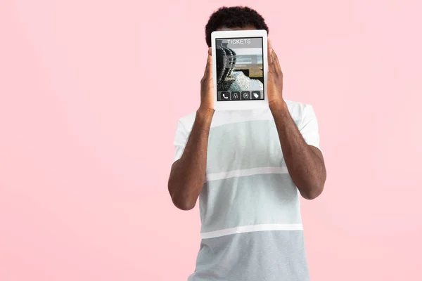 Hombre afroamericano mostrando tableta digital con aplicación de boletos, aislado en rosa - foto de stock