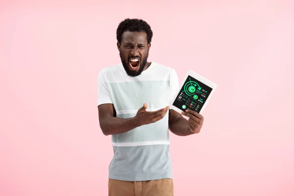 Hombre afroamericano emocional gritando y mostrando tableta digital con aplicación de infografía, aislado en rosa - foto de stock