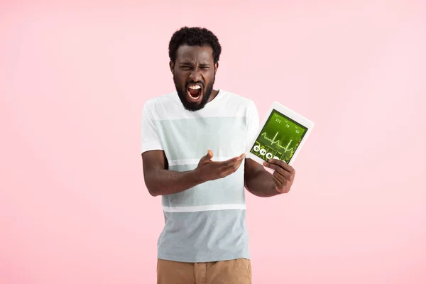 Emotional african american man screaming and showing digital tablet with health app, isolated on pink — Stock Photo