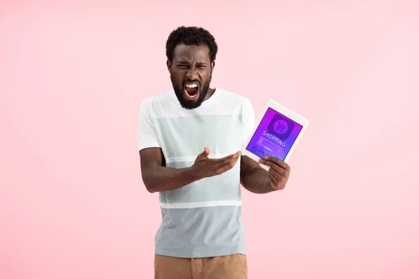 Homem afro-americano emocional gritando e mostrando tablet digital com aplicativo de compras, isolado em rosa — Fotografia de Stock