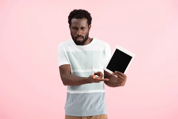 Verwirrter Afroamerikaner zeigt digitales Tablet mit leerem Bildschirm isoliert auf rosa — Stockfoto