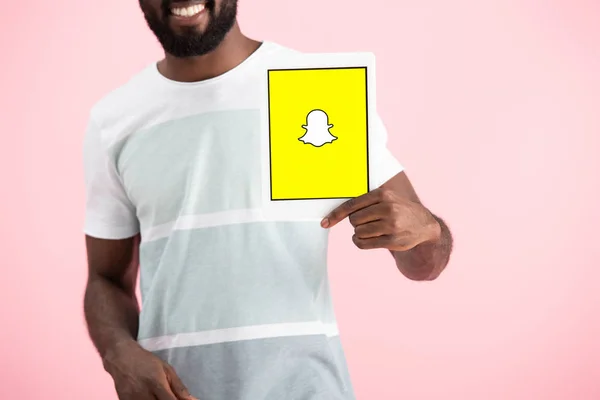 KYIV, UKRAINE - MAY 17, 2019: cropped view of african american man showing digital tablet with Snapchat app, isolated on pink — Stock Photo