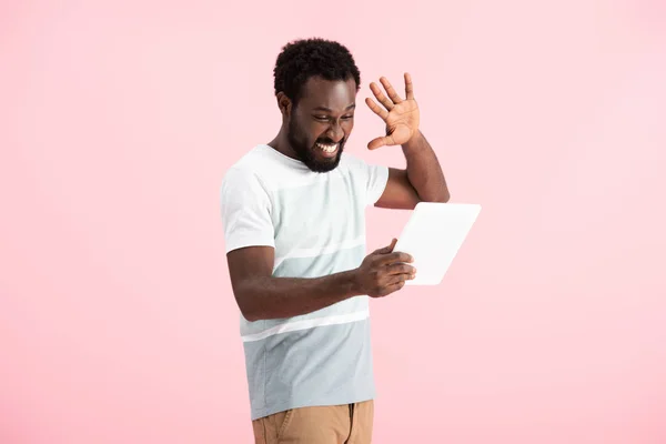 Heureux homme afro-américain geste et avoir chat vidéo sur tablette numérique isolé sur rose — Photo de stock