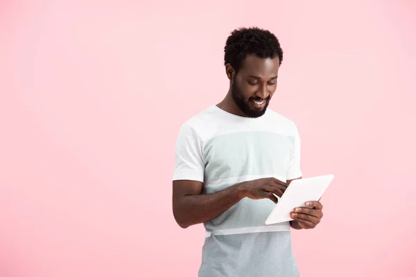 Sonriente afroamericano hombre utilizando tableta digital aislado en rosa - foto de stock