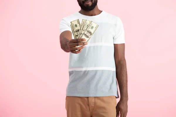 Vista cortada de jovem afro-americano segurando notas de dólares, isolado em rosa — Fotografia de Stock