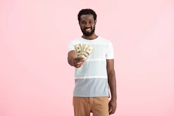Joyeux homme afro-américain tenant des billets en dollars, isolé sur rose — Photo de stock
