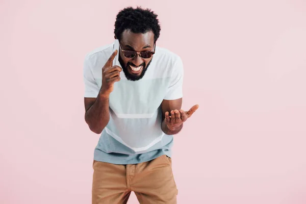 Emotionale afrikanisch-amerikanische Mann mit Sonnenbrille spricht auf Smartphone, isoliert auf rosa — Stockfoto