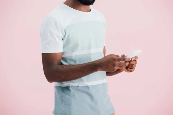 Vista recortada del hombre afroamericano utilizando un teléfono inteligente, aislado en rosa - foto de stock