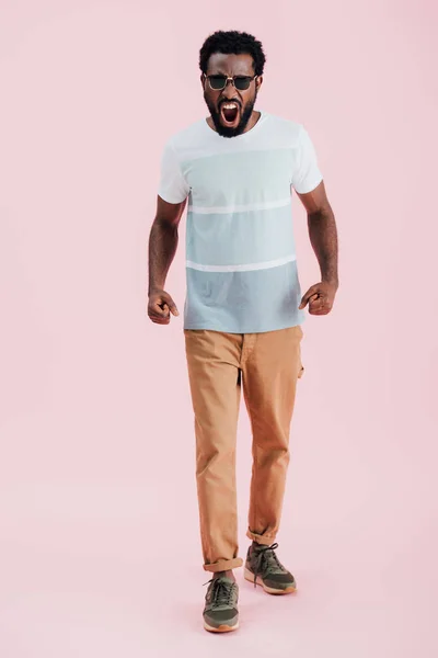 Agresivo africano americano de hombre en gafas de sol gritando aislado en rosa - foto de stock