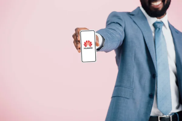 Kyiv, ukraine - 17. Mai 2019: Ausschnittansicht eines afrikanisch-amerikanischen Geschäftsmannes im Anzug zeigt Smartphone mit Huawei-App, isoliert auf rosa — Stockfoto