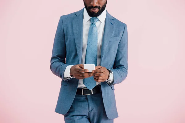 Vista ritagliata di uomo d'affari afroamericano utilizzando smartphone, isolato su rosa — Foto stock