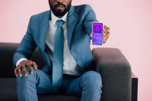 Vista cortada do empresário afro-americano mostrando smartphone com aplicativo de compras, isolado em rosa — Fotografia de Stock