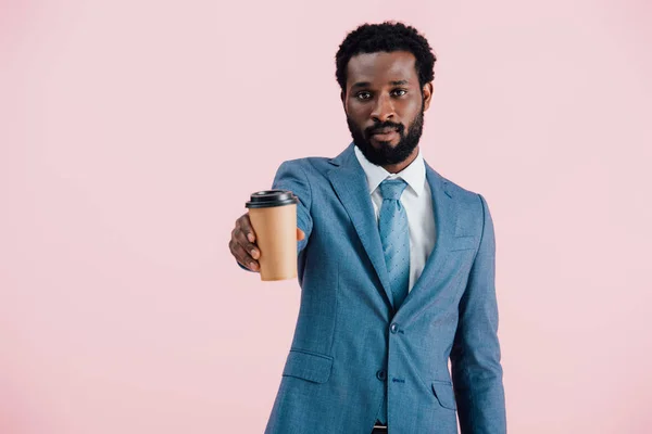 Empresario afroamericano serio sosteniendo café para llevar, aislado en rosa - foto de stock