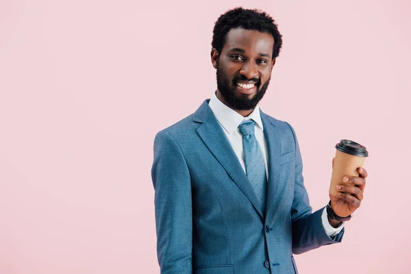 Счастливый африканский американский бизнесмен держит кофе, чтобы пойти, изолированы на розовый — стоковое фото