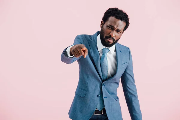 Angry african american businessman in suit pointing isolated on pink — Stock Photo