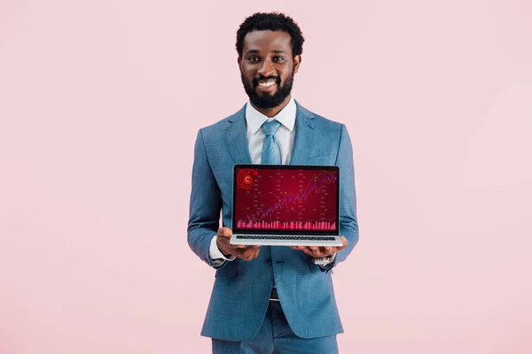 Lächelnder afrikanisch-amerikanischer Geschäftsmann zeigt Laptop mit Grafik isoliert auf blau — Stockfoto