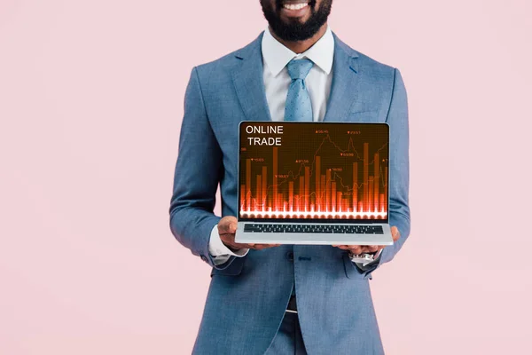 Vista cortada de sorridente empresário afro-americano mostrando laptop com comércio on-line isolado em azul — Fotografia de Stock