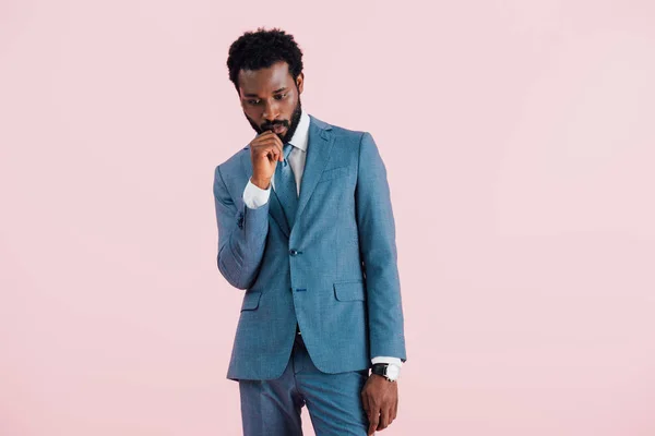 Hombre de negocios afroamericano pensativo en traje, aislado en rosa - foto de stock