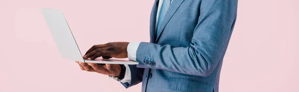 Vue recadrée de l'homme d'affaires afro-américain en utilisant un ordinateur portable isolé sur rose — Photo de stock