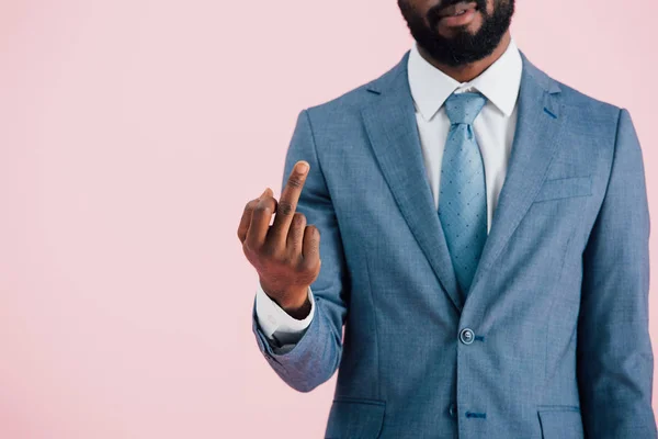 Обрізаний вид афроамериканського бізнесмена в костюмі і краватці, що показує середній палець, ізольований на рожевому — стокове фото