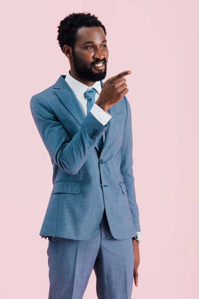 Молодий африканський бізнесмен, який посміхається, вказує на ізольованість на рожевому — стокове фото