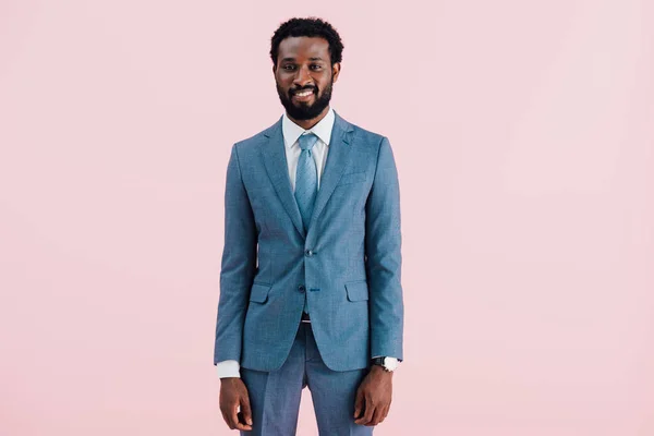 Усміхнений афроамериканський бізнесмен у костюмі, ізольований на рожевому — стокове фото