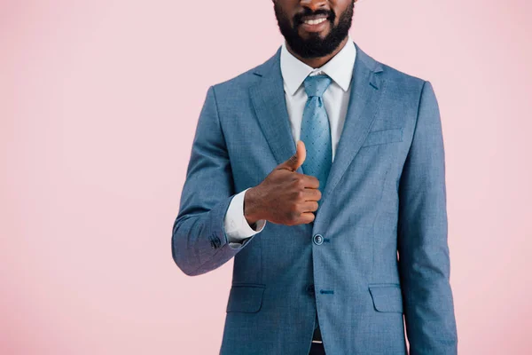 Vista recortada del hombre de negocios afroamericano en traje que muestra el pulgar hacia arriba, aislado en rosa - foto de stock