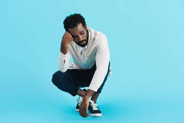 Chateado afro-americano homem sentado isolado no azul — Fotografia de Stock