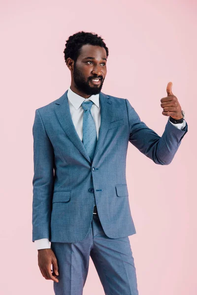 Joven hombre de negocios afroamericano en traje mostrando el pulgar hacia arriba, aislado en rosa - foto de stock