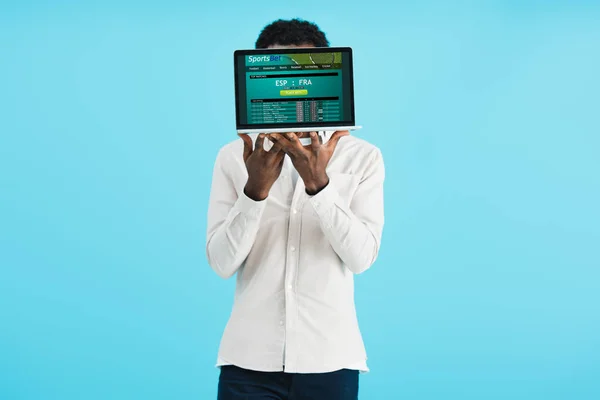 Африканский американец показывает ноутбук со спортивным сайтом, изолированным на синий — стоковое фото