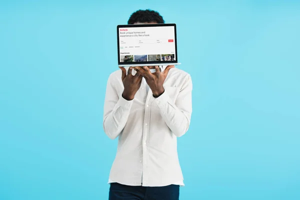 Київ, Україна-17 травня 2019: афроамериканець людина показує ноутбук з airbnb сайт, ізольований на синьому — стокове фото