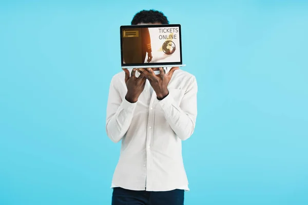 Afrikanischer Amerikaner zeigt Laptop mit Online-Tickets isoliert auf blau — Stockfoto