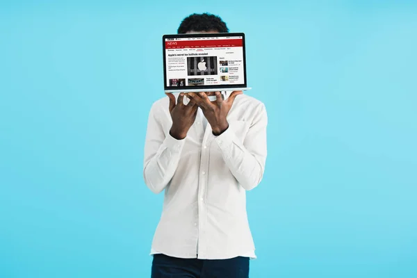 KYIV, UKRAINE - 17 MAI 2019 : Un homme afro-américain montrant un ordinateur portable avec le site d'information de la BBC, isolé sur bleu — Photo de stock