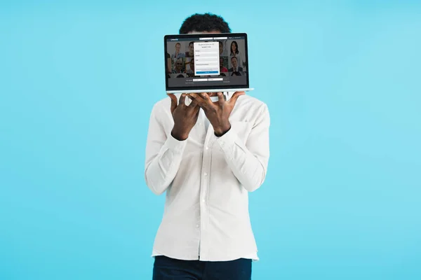 KYIV, UKRAINE - 17 MAI 2019 : Un homme afro-américain montre un ordinateur portable avec un site Web linkedin, isolé sur bleu — Photo de stock